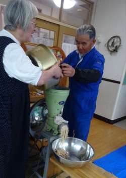 伊藤さんが大豆をみそすり機で潰しています。